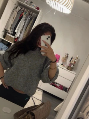 Grå oversized stickad tröja 3 kvarts - Mysig grå stickad tröja med oversized passform och breda ärmar. Tröjan har en enkel, klassisk design utan synligt märke och är perfekt för lager på lager. Materialet ser ut att vara mjukt och lite luddigt, vilket ger en avslappnad vibe.