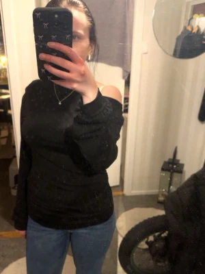 Svart offshoulder topp med puffärm - Snygg svart offshoulder topp med långa puffärmar. Toppens axlar är bara och den har en tight passform som framhäver figuren. Perfekt för dig som vill ha en trendig och stilren look.