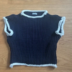 Mörkblå stickad topp från Meet Me There - Säljer en mörkblå stickad topp från Meet Me Ther i storlek XXS/XS. Toppen har korta ärmar och är ribbstickad med vita kanter runt hals, ärmslut och nederkant. Nästintill oanvänd, inga defekter💙💙