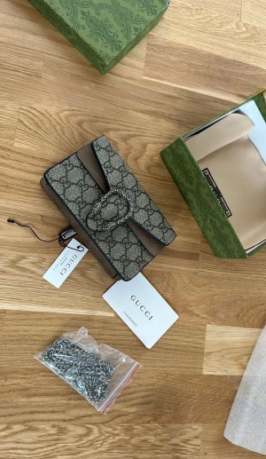 Gucci Dionysus axelväska med kedja - Snygg Gucci Dionysus axelväska med klassiskt GG-mönster i beige och brunt. Väskan har en silverfärgad kedja. 