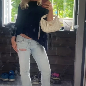 Mörkblå stickad poncho Holly & Whyte - Snygg mörkblå stickad poncho från Holly & Whyte by Lindex. Asymmetrisk form med tre dekorativa guldfärgade knappar vid axeln. Perfekt att slänga över en t-shirt för extra stilpoäng. Mjuk och skön känsla, passar dig som gillar en chill och trendig look.