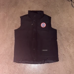 Svart väst från Canada Goose M - Svart dunväst från Canada Goose originals  påsen ingår som ni ser på bilden. Den passar S och M om man vill ha det lite tajt 
