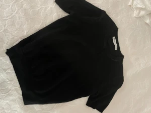 Svart stickad topp från ZARA - Svart stickad topp från ZARA med rund hals och korta ärmar. Enkel och stilren design som är lätt att matcha. Mjuk och skön stickad kvalitet som känns nice mot huden. Perfekt för dig som gillar minimalistisk stil.