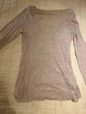 Beige långärmad topp med spets från Intimissimi (S) - Superfin beige långärmad topp från Intimissimi med v-ringning och detaljerad spets runt halsen och ärmsluten. Mjuk och tunn kvalitet med kashmirblandning, perfekt för dig som gillar en feminin och chill stil.