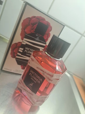 Victoria Flower Orchid parfym 100ml - Victoria Flower Orchid från Maison Alhambra är en Eau de Parfum med en snygg rosa flaska och modern design. Volymen är 100ml, perfekt för dig som vill sticka ut med en unik och trendig parfym.