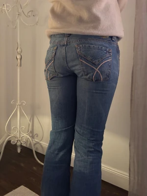 Blå bootcut jeans från Tommy Hilfiger - Snygga blå jeans från Tommy hilfiger  med bootcut passform och låg midja, slitningar framtill