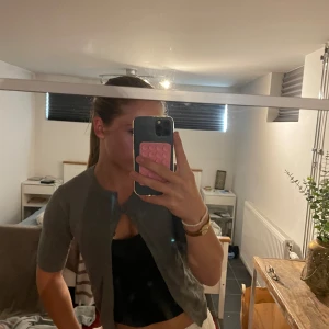 Grå kofta från Zara, kort ärm - Grå kofta från Zara i storlek S. Modellen har korta ärmar och knäppning framtill. Koftan är i mjukt stickat material och har en enkel, klassisk design som är lätt att matcha med olika outfits.