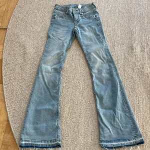 Ljusblå bootcut jeans med slitna kanter - Ljusblå jeans med bootcut passform och lågmidjade. Jeansen är sprättade där nere och passar mig som är 170 cm, mer åt det för långa hållet än korta.