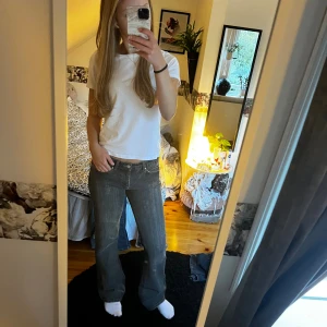 Mörkgrå bootcut jeans från Vila - Säljer ett par mörkgrå jeans från Vila med bootcut passform och klassiska femficksdetaljer. Jeansen har låg midja och slitningar längs benen. Liiite slitage vid hälarna men inget som märks🤍