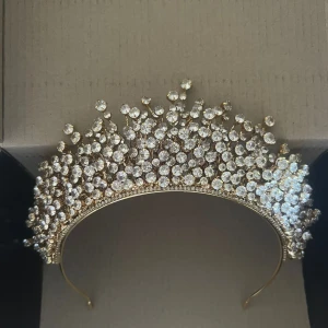 Glittrig tiara från lazurd i Guldpläterat - Superfin tiara från lazurd i guld med massor av glittrande stenar som ger en riktigt lyxig känsla. Tiaran har en unik, buskig design med gnistrande kristaller i olika höjder som verkligen drar blickarna till sig. Perfekt för dig som vill sticka ut och glänsa extra mycket. Vi kan diskutera priset 🙂