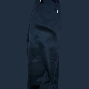 Svarta mjukisbyxor från Polo Ralph Lauren -  VERIFIED FRÅN VINTED Svarta mjukisbyxor från Polo Ralph Lauren med vit broderad logga på vänster höft och vit snörning i midjan. Byxorna har elastisk midja och muddar vid bensluten för en skön och avslappnad passform. Perfekta för chill eller träning.
