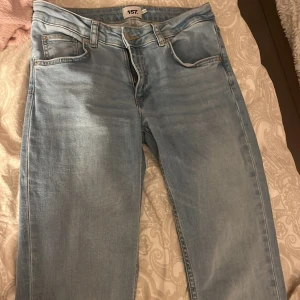 Bootcut ljusblå jeans från 157 - Säljer ett par ljusblå bootcut jeans från 157 med klassisk femficksdesign och snyggt skinnpatch bak i midjan. Jeansen har normal passform och är tillverkade i mjukt denimtyg som sitter skönt hela dagen.