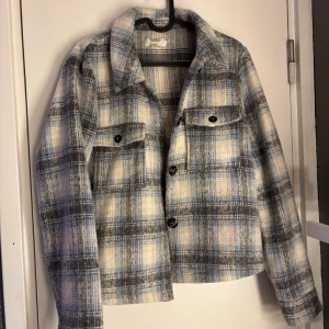 Rutig kappa från ONLY - Säljer en snygg rutig overshirt från ONLY i storlek L. Jackan har klassisk krage, knäppning framtill och två bröstfickor med knappar. 