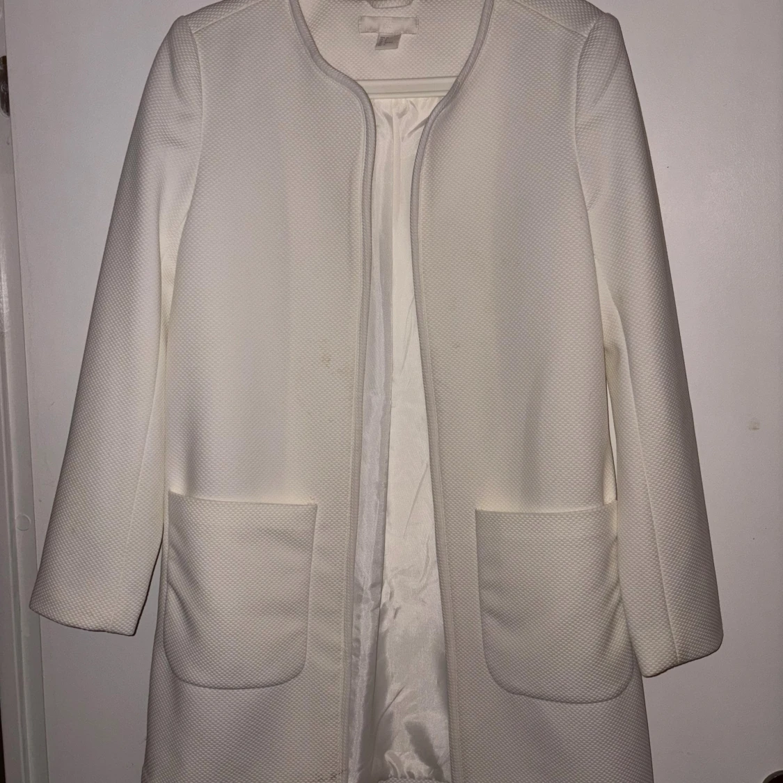 Vit strukturerad kappa med fickor