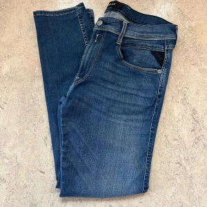Blå Replay Anbass jeans  - Säljer ett par helt nya blåa Replay Anbass jeans i storlek 32/30. Jeansen har en slim passform med klassisk femficksdesign och snygga detaljer vid fickorna. Tillverkade i stretchigt jeansmaterial för extra komfort. Perfekta för dig som gillar en modern och stilren look.
