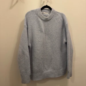 Ljusblå  stickad tröja från Zara - Mysig ljusgrå stickad tröja från Zara med rund halsringning och breda ribbade muddar vid ärmslut och nederkant. Perfekt för lager-på-lager och chill dagar. Enkel och stilren design som funkar till det mesta.
