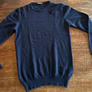 Mörkblå stickad tröja Stenströms - En klassisk mörkblå stickad tröja från Stenströms. Tröjan har rund halsringning, långa ärmar och ribbade muddar vid ärmslut och nederkant. Perfekt för lager-på-lager under kyliga dagar.
