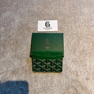 Grön korthålare från G - Snygg grön korthållare från G med deras ikoniska mönster. Tillverkad i skinn med flera kortfack och klassisk logga framtill. Kommer med originalask och certifikat. Perfekt accessoar för dig som vill ha något unikt och stilrent.