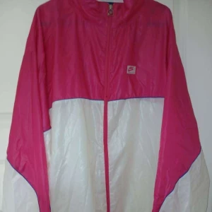 Nike vindjacka  - Retro vindjacka från Nike i färgblockad rosa och vit med blå piping. Jackan är i bra skick. Äkta såklart.