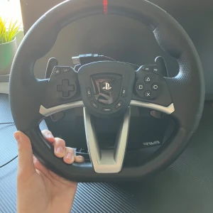Hori Racing Wheel Apex (RWA) för PlayStation / Xbox / Pc - Hori Racing Wheel Apex (RWA) för PlayStation 4/5 / Xbox / Pc. Komplett med originalkartong. Ratten har PlayStation-knappar, paddlar och USB-anslutning. Lättare damm syns men i övrigt fint skick, perfekt för racing- och bilspel.