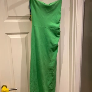 Grön långklänning från Zara - Snygg grön långklänning från Zara med smala axelband och rak passform. Klänningen har en enkel och stilren design, perfekt för dig som gillar färg. Materialet är mjukt och känns skönt mot huden. Passar dig som vill sticka ut med en cool look.