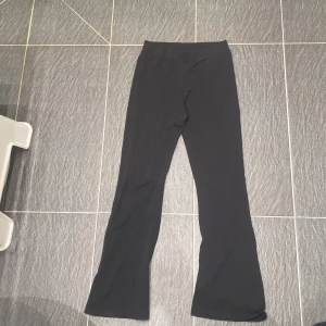 Svarta bootcut byxor från Kappahl - Svarta byxor från Kappahl i stretchigt material med bootcut-ben. De har en enkel, stilren design utan synliga detaljer och en bekväm midja. Perfekta för dig som gillar en klassisk look med lite utsvängda ben.