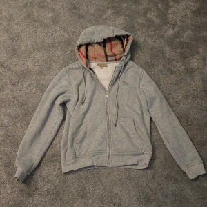 Burberry zip - En snygg burberry zip. Som har använts mycket men inte några defekter förutom att armbågarna slitigt som händer på de flesta tröjorna, derför lägre pris. Drar man upp armarna så syns det inte och det går även att måla över med grå tygfärg om man orkar!