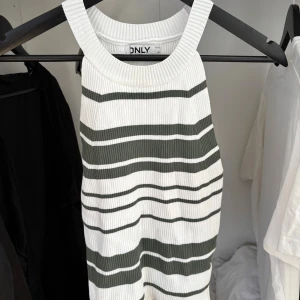 Randig ribbad topp från ONLY - Superfin ribbad topp från ONLY i vitt med gröna och svarta ränder. Ärmlös modell med breda axelband och tight passform. Perfekt för en fräsch och avslappnad look.