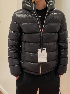 Moncler aubert jacka - Svart junior dunjacka från moncler, med allting og, alltså saker som väskan som jackan kom med (bild 5) och etiketterna och även moncler galjen. Jackan är köpt ifrån deras hemsida, jag är den enda ägaren av jackan. Om ni vill ha några mer bilder på jackan eller om ni har frågor osv så är det bara att skriva. Utropspris på 4000
