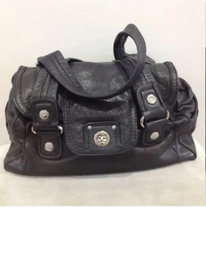 Svart handväska från Marc by Marc Jacobs - Cool svart handväska i skinn från Marc by Marc Jacobs med silverfärgade detaljer och logga framtill. Insidan har ett mönstrat foder med stora vita bokstäver på svart bakgrund. Väskan har praktiska handtag och dragkedja, perfekt för dig som gillar stilrena accessoarer.