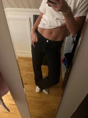 Svarta low waist straight jeans - Säljer ett par svarta jeans från bikbok med låg midja och raka ben. Modellen är straight och de har klassisk femficksdesign med silverfärgade nitar och knapp. Materialet är jeans och passformen är normal. Perfekta om du gillar en chill och enkel stil. Nypris 599kr.