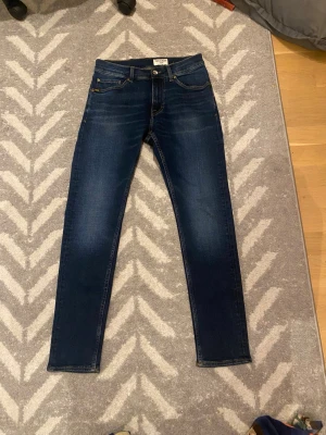 Mörkblå jeans Evolve 28/30 - Snygga mörkblå jeans från Evolve i klassisk femficksmodell. Jeansen har en slim/ straight passform. Perfekt för en stilren och morden look nu pris 1400 mitt pris 300 för att de var fel storlek för mig, använd 2 gånger 