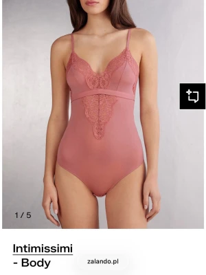 Rosa spetsbody från Intimissimi - Supersnygg rosa body från Intimissimi med tunna axelband och v-ringad spetsdetalj framtill. Bodyn har en mjuk, följsam passform och dekorativ spets längs bysten och magen som ger en romantisk vibe.