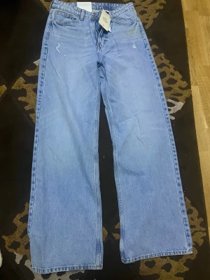 Blå wide high waist jeans från Askin - Säljer ett par ljusblå jeans från Askin med hög midja och breda ben. Klassisk femficksmodell i mjukt bomullsjeansmaterial. Snyggt minimalistisk look utan slitningar eller dekorationer. Perfekta till sneakers eller boots.