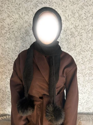 Balaklava  - Säljer en brun omlottväst med bälte i midjan. Västen har en rak och loose passform och är tillverkad i ett tjockare material som ger en snygg siluett. Perfekt att styla över en hoodie eller tröja för extra lager. Färgen är djupbrun och västen har en enkel, stilren look.