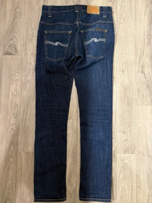 Nudie Jeans Thin Finn Organic Dry Blå Jeans W30 L32 - Nudie Jeans Thin Finn ’Organic Dry Ecru Embo’ jeans I Dry mörkblå färg i fint skick i storlek W30/L32. Mått - Midja: 38cm, Benlängd: 101cm. Modellen är 185cm & 63kg. Hör av dig vid funderingar!🤩