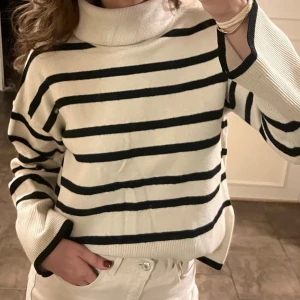 Randig stickad polotröja svart och vit - Säljer en vit polotröja med svarta horisontella ränder. Tröjan har en hög, bred polokrage och långa ärmar med ribbade muddar. Storlek XS, men passar bra på mig som bär S vanligtvis. 