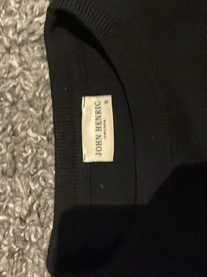 Svart merinoull tröja passar small o x-small - Snygg svart stickad tröja från John Henric i storlek S. Tröjan har rund hals och långa ärmar, perfekt för dig som gillar stilrena och enkla plagg. Materialet är mjukt och skönt, och passar bra till både jeans och chinos.