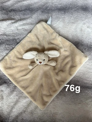 Beige snuttefilt med kanin -  snuttefilt i beige med en söt kanin i mitten. Filten är fyrkantig. Perfekt som tröst eller mys för små barn. Kaninens öron är vita och filten är lätt att ta med sig.🌸Fint använt skick 