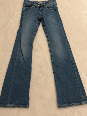 Blå bootcut jeans Gina Tricot 152 - Säljer ett par klassiska blå jeans från Gina Tricot i storlek 152. Jeansen har bootcut-modell med utsvängda ben och normal passform. Tillverkade i mjukt denimtyg med snygga slitningar och femficksdesign. Perfekta för en avslappnad och trendig look.🫰🏼 Nypris ca 350kr.