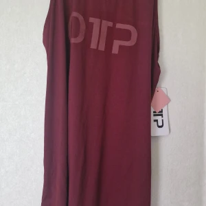 Vinrött träningslinne från OTP - Snyggt vinrött träningslinne från OTP med sportig rygg. Linnet har ett stort tryck med OTP-loggan framtill och är gjord i mjukt polyester-material som känns skönt mot huden. Perfekt för dig som gillar en enkel look. Nytt med prislapp.