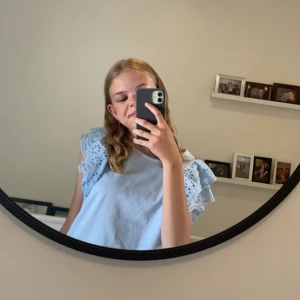 Ljusblå blus med volangärmar - Supersöt ljusblå blus med broderade volangärmar. Använde på en skolavslutning och inte använt sen dess, super fin färg och skönt material! 158/164 storlek 