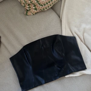 Svart skinnkorsett från Gina Tricot - Säljer en svart korsett-topp från Gina Tricot i skinnimitation, använd vid ett tillfälle