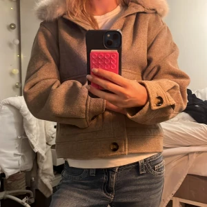 Beige kappa med fuskpäls från H&M  - Säljer en beige kappa från H&M med en len fuskpäls som går att ta bort om man vill det. Kappan är lite croppad och har stora knappar. Jätte fin nu till hösten ❤️ pris kan diskuteras ☺️🫰