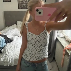 Vit prickig linnetopp - Säljer en söt vit linnetopp med svarta prickar och smala axelband. Lite insydda axelband❤️