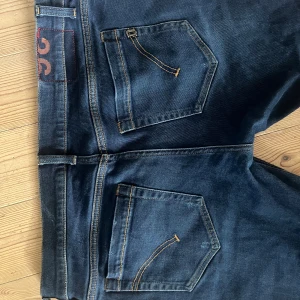 DonDup jeans i mörkblå - Mörkblå DonDup george jeans med klassisk femficksdesign och snygga kontrastsömmar. Jeansen har en smal passform och är tillverkade i slitstarkt denim, använda 1 gång i nyskick!.