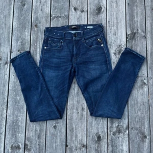 Replay Anbass jeans blå, stl 28 - Snygga blå Replay Anbass jeans i klassisk femficksmodell. Jeansen har smal passform, normal midja och raka ben. Tillverkade i stretchigt denim för extra komfort. Perfekta för dig som gillar stilrena och moderna jeans med diskreta detaljer. Pris kan diskuteras!!!! Och det finns noppor vid kedjan och fickorna men inte något som stört mig!