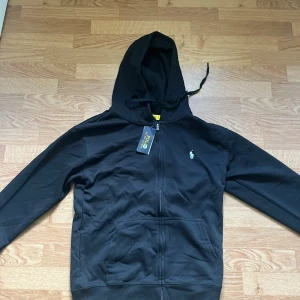 Svart hoodie från Polo Ralph Lauren - Svart hoodie från Polo Ralph Lauren med klassisk broderad logga på bröstet. Helt ny oanvänd i storlek M men passar även S fråga gärna om ni undrar något😁.