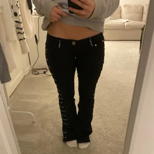 Svarta jeans med nitar - Svarta jeans med låg midja. Snygga silverfärgade nitar längs fickor och sidorna av benen ger en cool vibe. Vet ej vart dom är ifrån då ja köpt dom tidigare på vinted och den tidigare säljaren har sytt om jeansen till bootcut och sytt in midjan! ( har bilder på de) sen har även några diamanter åkt av som ni ser på fjärde bilden! Annars ass coola jeans❤️