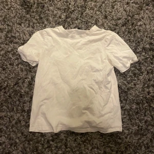 Vit t-shirt från Pieces, storlek S - En basic vit t-shirt från Pieces i storlek S. T-shirten har rund halsringning och korta ärmar, tillverkad i mjuk bomull. Perfekt att matcha med jeans eller shorts för en clean och enkel look.